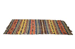 A 20th century Kilim rug (AF) on a blue, cream, red, yellow and black ground, with tassles.
