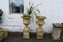 A large pair of urns together with a pair of square pedestals.