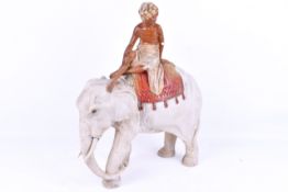 A 1930's period plaster figure of a boy wearing a turban riding a white elephant.