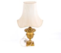 A gilt metal urn shaped table lamp. Raised on a square base.