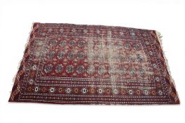 A Turkman Bokhara red ground rug with blue, orange and white geometric pattern, heavy wear.