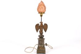 Bronze finish table lamp with eagle supporting a flame lampshade.