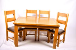A contemporary light oak extendable dining table and set of four matching chairs.