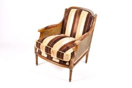 A French bergere mahogany style armchair with stripped brown upholstery.