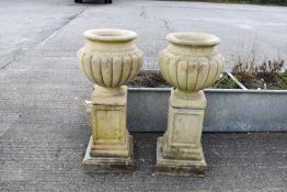 A pair of reconstituted stone bulbous urns on square plinths. Three pieces each, total H92cm.