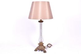 A large brass and cased glass table lamp. raised on a tripod base.