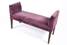 A modern upholstered window seat. Purple fabric raised on stained beech tapering supports.