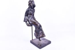 A bronze effect sculpture of a woman in a long dress. Raised on a rectangular plinth.