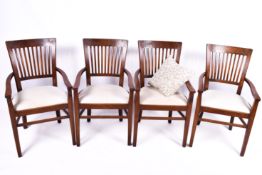 A set of four wooden open armchairs. Having a slatted backrest with cream upholstered padded seats.