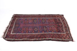 An antique red ground rug with geometric blue pattern.