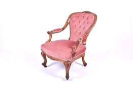 A Victorian walnut nursing chair with pink upholstory.