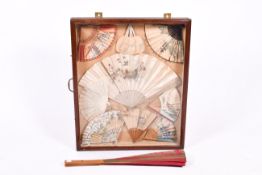 A mounted display of nine decorative fans and one other large red fan.