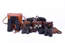 A collection of eight binoculars.
