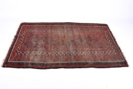 An antique red ground rug with blue geometric pattern. Heavy wear.