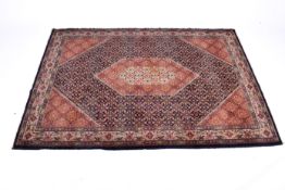 A Persian Bidjar style wool rug on a blue and red ground.