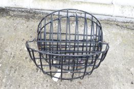 Three black wire wall mounted horse feeders.