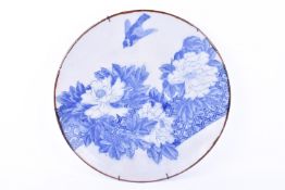 A Japanese blue and white charger decorated with birds swooping over flowers.