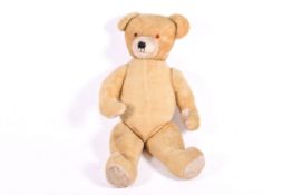 A large circa 1960s English plush jointed teddy bear. Having straw filling and plastic eyes.