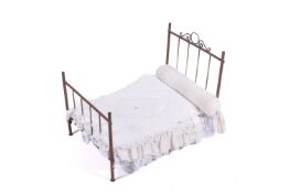 A scratch built copper doll's bed frame. With blankets and cushions, H57cm x W71cm x D47cm.