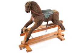 A vintage wooden P C & R Schaay rocking horse. Raised on a wooden stand with a green padded saddle.