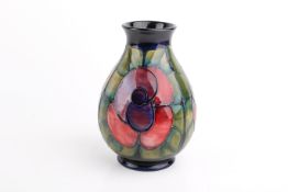 A blue ground Moorcroft vase with repeating pink rose and foliage pattern.