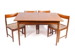 A 1960s teak extending dining table and four chairs. Table opens to reveal fold-out leaves.