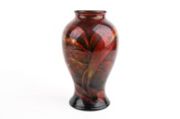 A brown ground Moorcroft vase with autumnal colours. Decorated with fish, reeds and flowers.