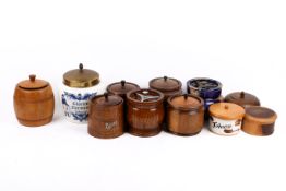 A collection of eleven assorted wooden or ceramic tabacco storage jars.