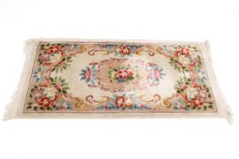 A Chinese style rectangular wool rug on a cream ground. Having floral motifs.