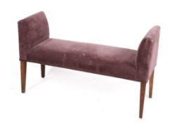A modern upholstered window seat. Purple fabric raised on stained beech tapering supports.