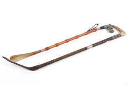 A riding crop with hallmarked silver collars and a horn handle with a shoe horn with carved dog