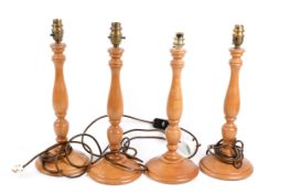 A set of four contemporary turned wooden candlestick type table lamps. Raised on circular bases.