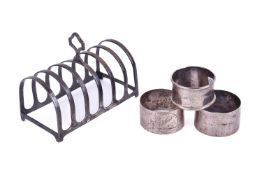 A silver toast rack and three napkin rings. Assorted hallmarks, toast rack width 11.