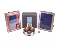Four pieces of hallmarked silver. Comprising two photograph frames, a bottles stand, and a thimble.