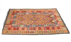 A beige ground rug with blue and red/pink geometric pattern.