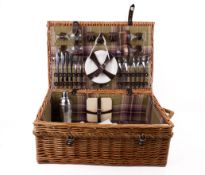 A large wicker picnic basket with contents, mostly for four.