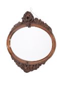 A carved walnut oval wall mirror. Having scroll and shell crest.