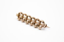 A yellow metal bar brooch with linked S-motifs. Unmarked but tested as 9ct gold, L4.