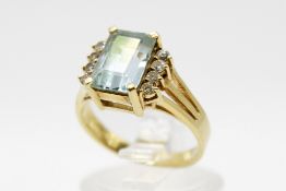 A yellow metal and aquamarine cluster ring. The emerald cut stone circa 1cm x 0.