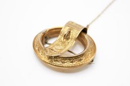 A yellow metal brooch in the form of a buckle.