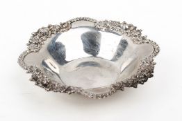 A white metal silver dish stamped 'Stirling'. Having lobed and ornate floral rim.