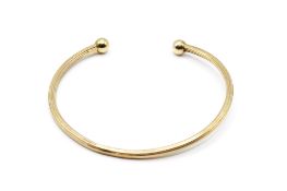 A 9ct gold torque bangle. Ribbed, with import hallmarks, weight 4.6g.
