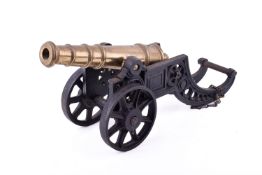 A brass model of a cannon on a cast iron carriage.