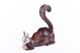 A vintage carved nut dish in the form of a squirrel with a nut.