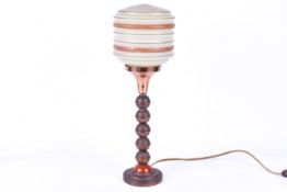 An Art Deco ball table lamp with striped opaque glass shade. Raised on a circular base.