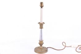 A brass and glass candlestick type table lamp. Raised on a circular base with leaf decoration.