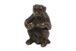 A Japanese style bronze model of a seated monkey holding a fruit. Unsigned, H4.5cm.