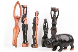 Six 20th century wood carvings of standing African figures and a hippo.