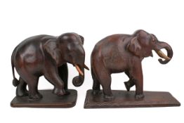 Two carved wooden elephants. Both with white painted tusks, on shallow platforms, largest H29.5cm.