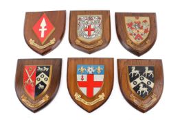 Six coats of arms mounted on wooden shield backs.